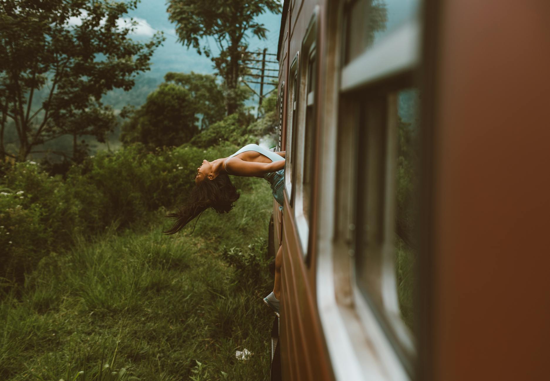 unrecognizable woman leaning back standing in train and holding on to handrails